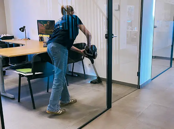 Technicienne JP Wash aspirant le sol d’un bureau pour nettoyage professionnel des espaces de travail.