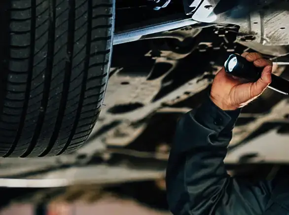 Technicien inspectant le dessous d’une voiture présentée par JP Wash au contrôle technique.