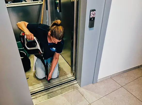 Technicienne JP Wash nettoyant un ascenseur dans des parties communes d’immeuble.