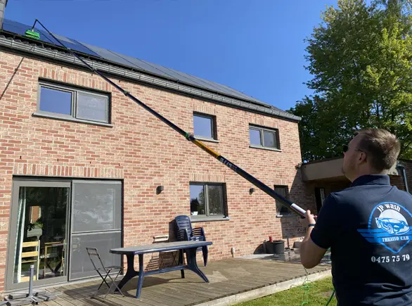 Technicien JP Wash nettoyant des panneaux solaires en toiture avec matériel professionnel.
